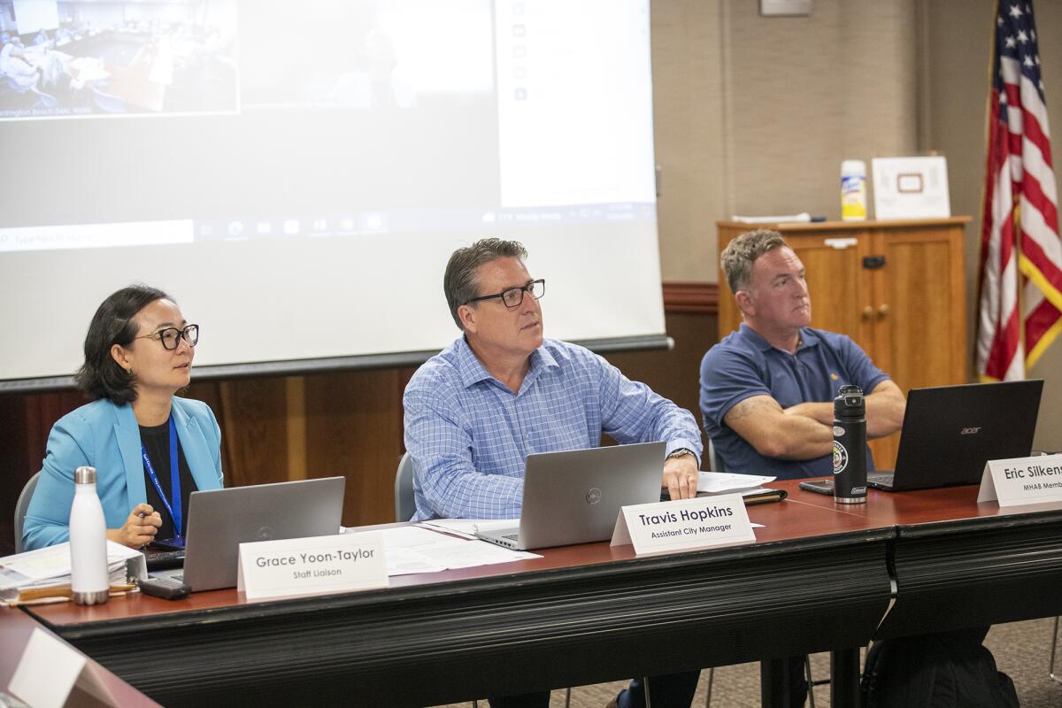 Grace Yoon-Taylor, left, Travis Hopkins and Eric Silkenson listen to a speaker during Monday's meeting.
