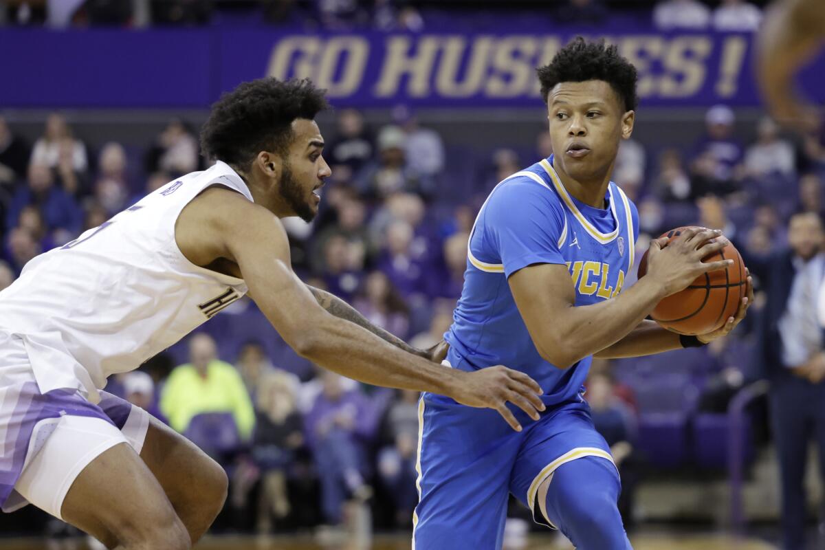 UCLA guard Jaylen Clark works to keep the ball away from Washington guard Jamal Bey during the second half Sunday.