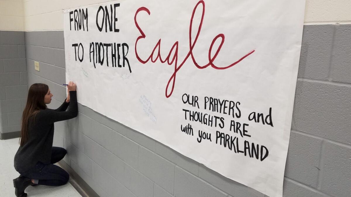 Lizzie Dagg, 18, a senior at Argyle High School, signs a poster for victims of the deadly Florida shooting..