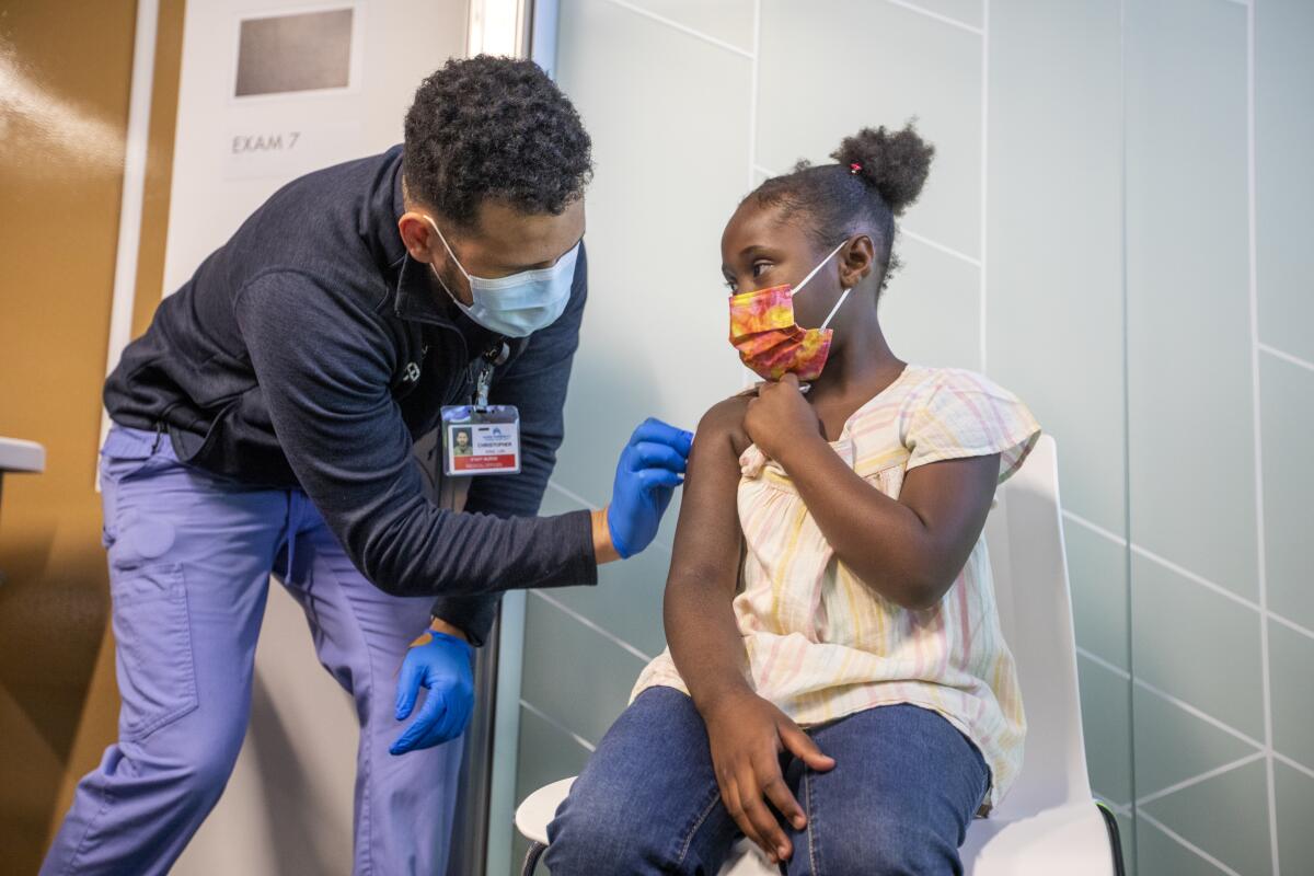 A medical worker prepares to give a girl a vaccine