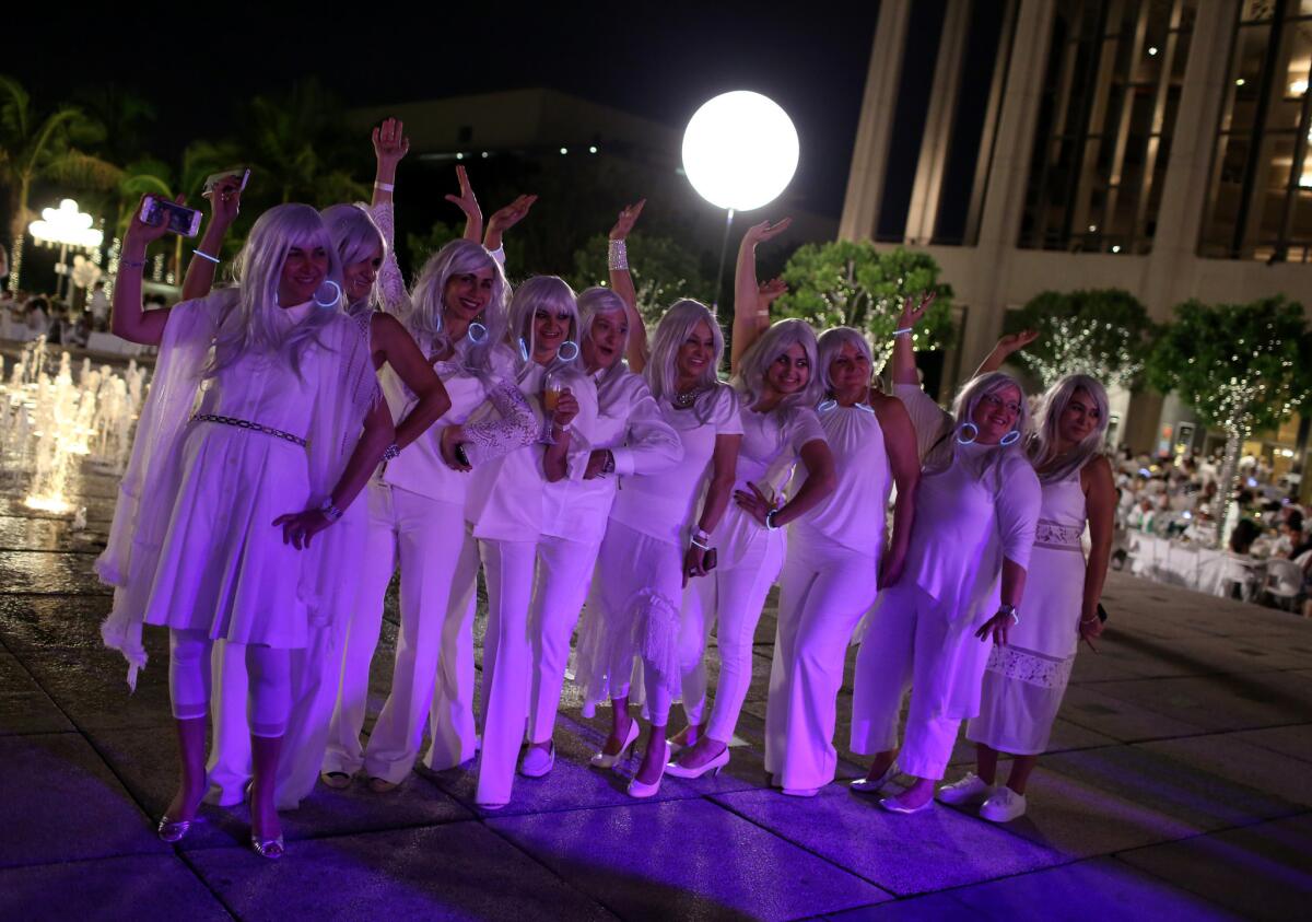 Ladies donning white wigs pose for a picture at Diner en Blanc.