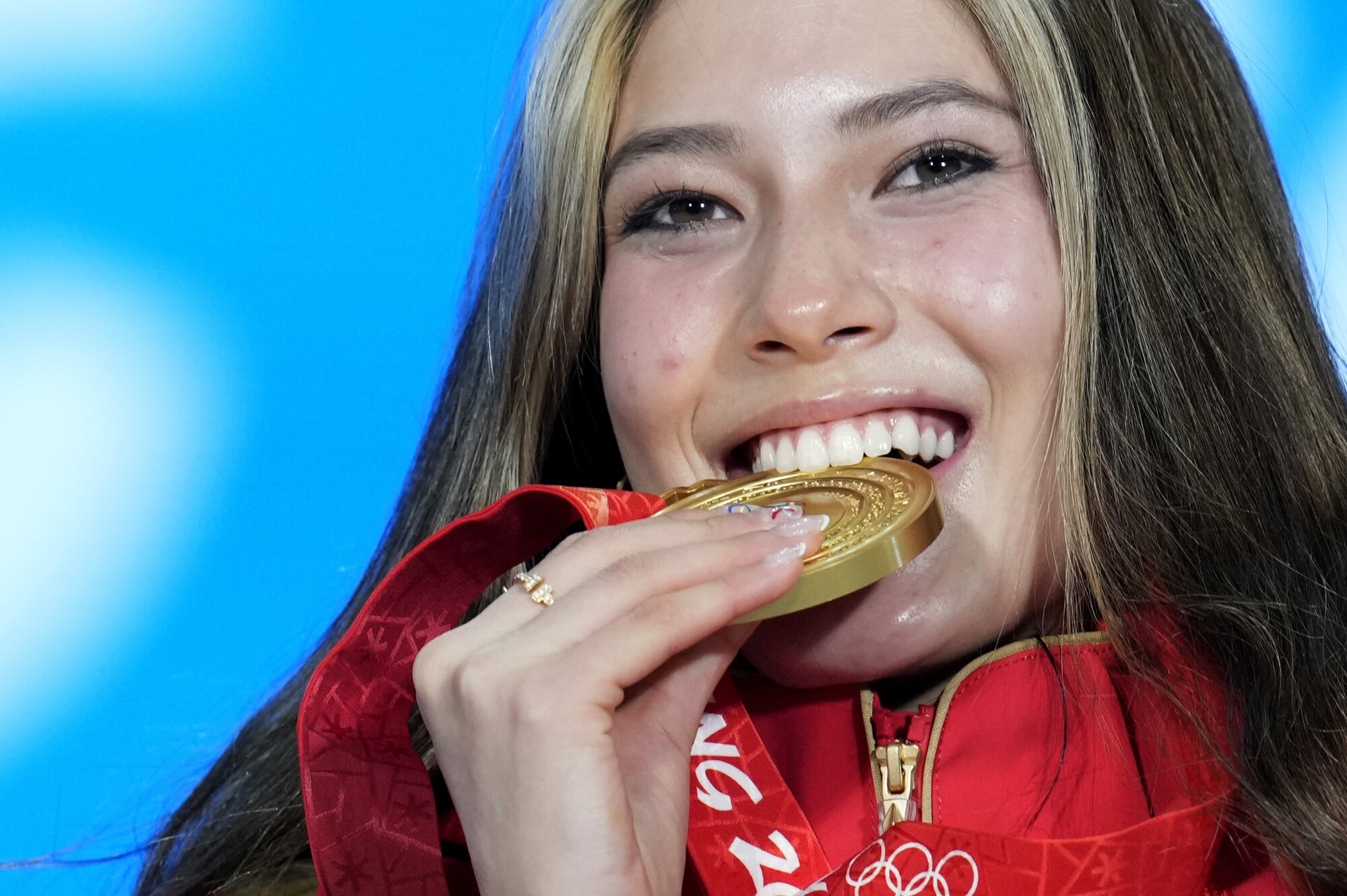China freestyle skier Eileen Gu of China poses with her gold medal in her mouth.