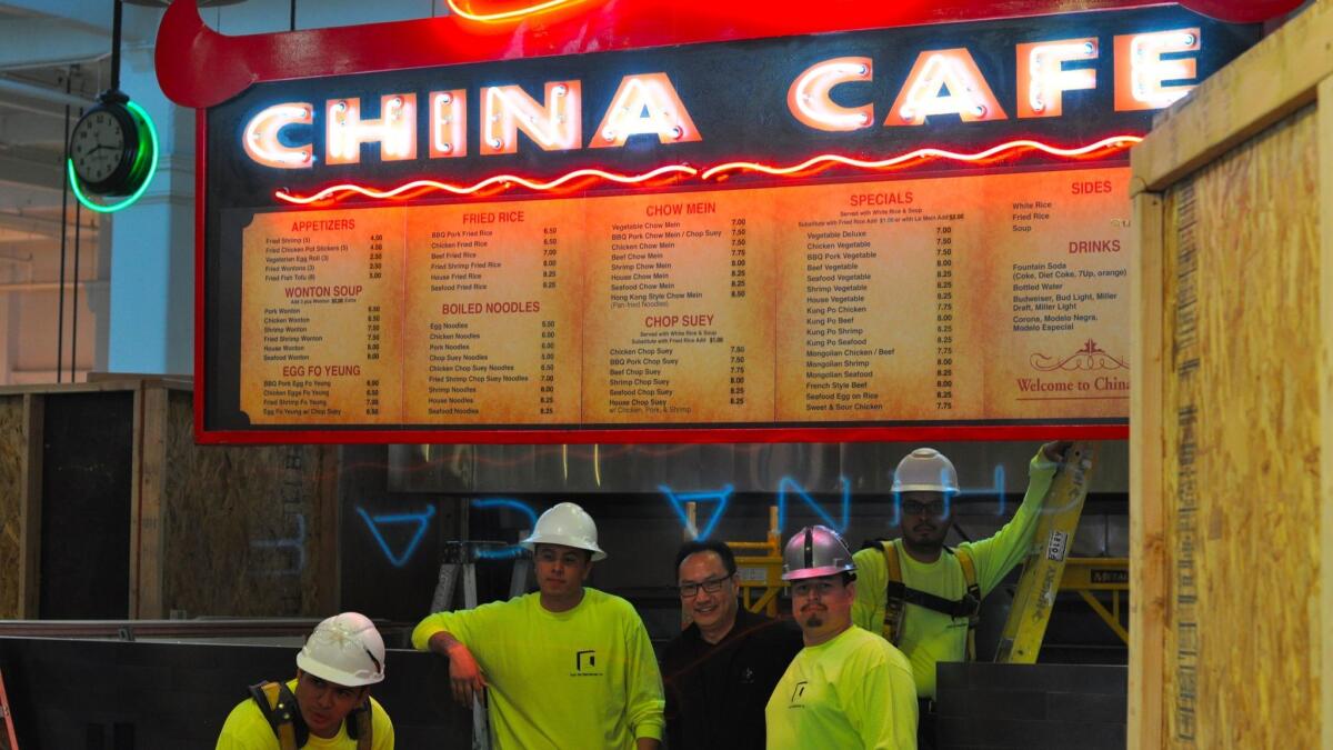 China Café owner Rinco Leung (without the hardhat) poses with workers after the cafe's sign is turned back on. (Amy Scattergood / Los Angeles Times)
