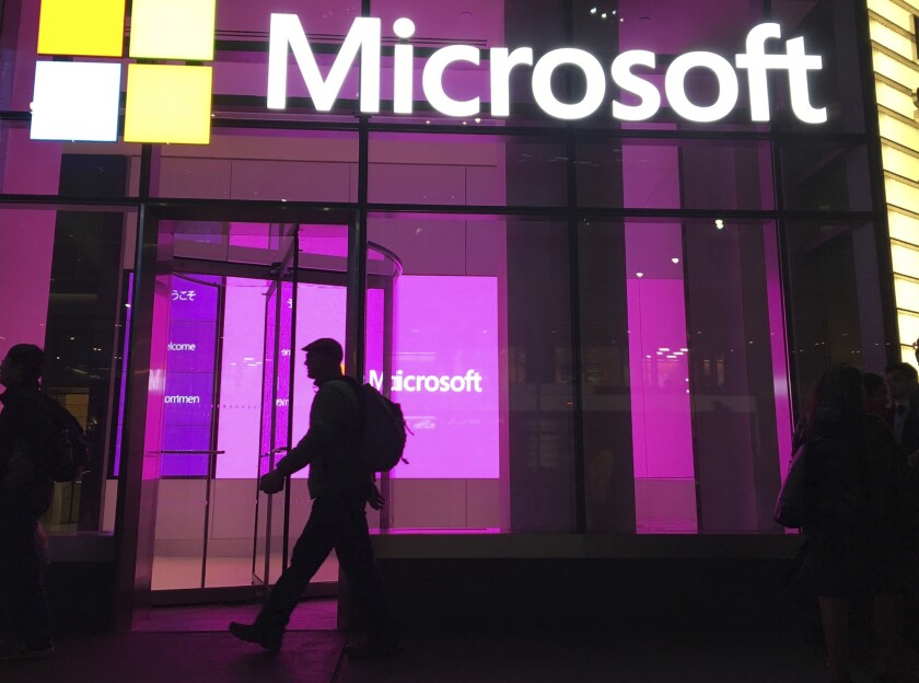 FILE - In this Nov. 10, 2016, file photo, people walk near a Microsoft office in New York. Microsoft, on an accelerated growth push, is buying speech recognition company Nuance in a deal worth $19.7 billion including debt. (AP Photo/Swayne B. Hall, File)
