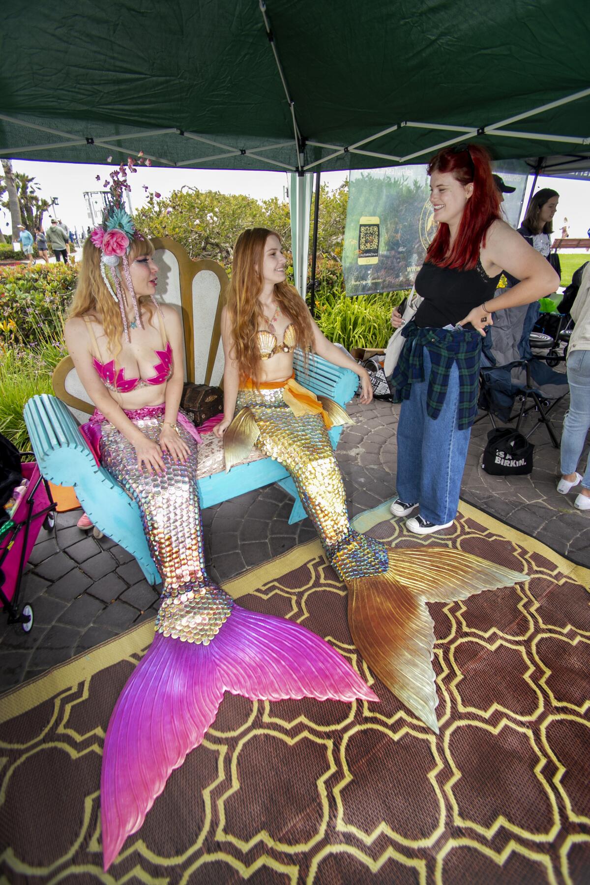 Orange County Mermaids Artemesia and Avalon chat with a visitor at KelpFest in Laguna Beach on Saturday.