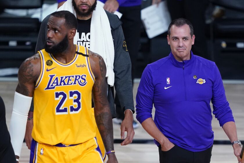 Lakers forward LeBron James, left, and coach Frank Vogel walk onto the court during a timeout.