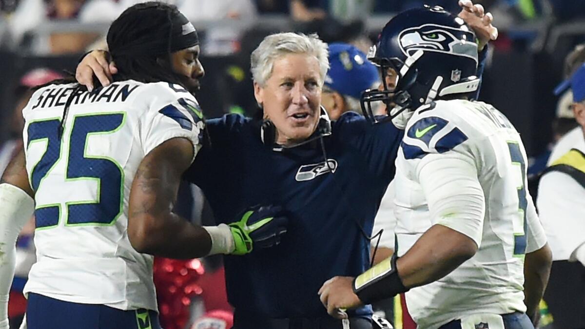 Seattle Seahawks Coach Pete Carroll, center, congratulates cornerback Richard Sherman, left, and quarterback Russell Wilson after a late touchdown against the Arizona Cardinals on Dec. 21.