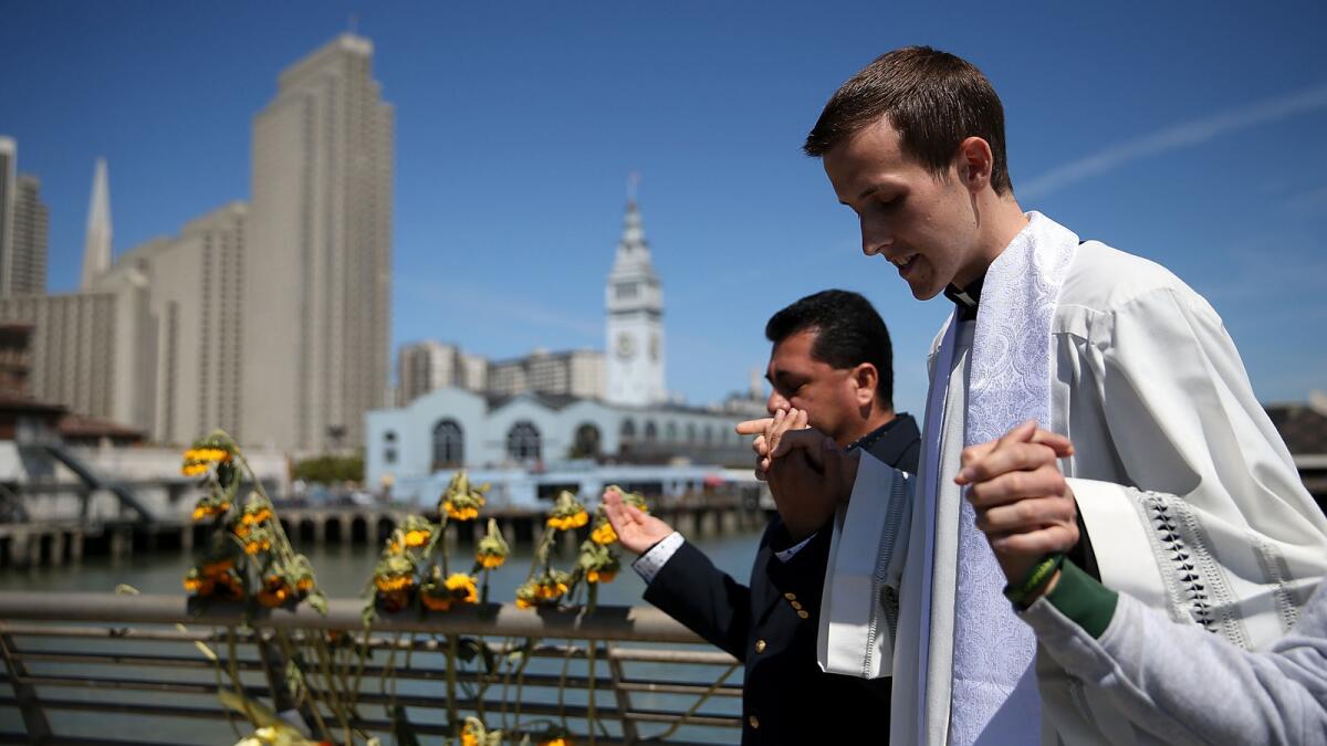 Father Cameron Faller, right, associate pastor at the Church of the Epiphany, and Julio Escobar of the Archdiocese of San Francisco Restorative Justice Ministry conduct a prayer service at the site where 32-year-old Kathryn Steinle was killed.