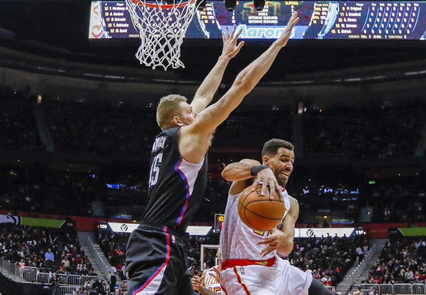 Hawks forward Thabo Sefolosha, right, passes the ball around Clippers center Cole Aldrich during the first half.