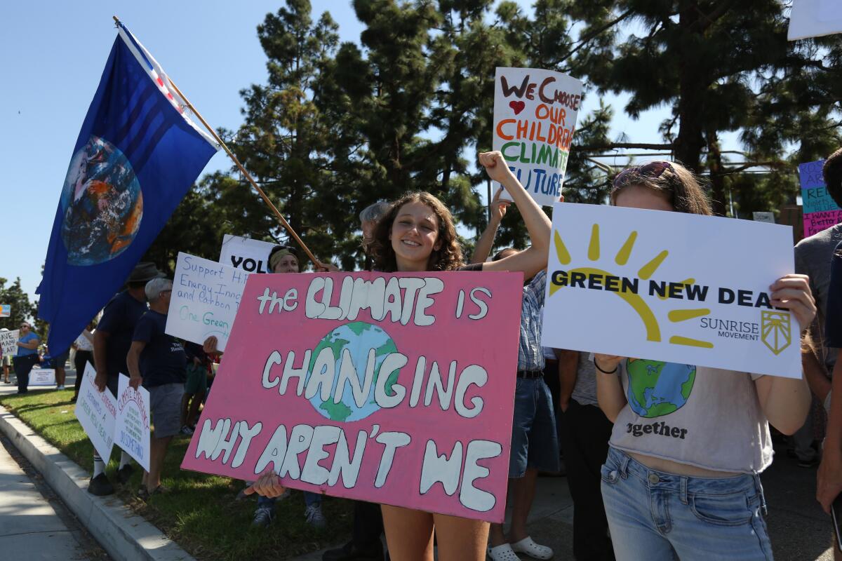 Protesters hold signs during a climate change protest in 2019 in Irvine.