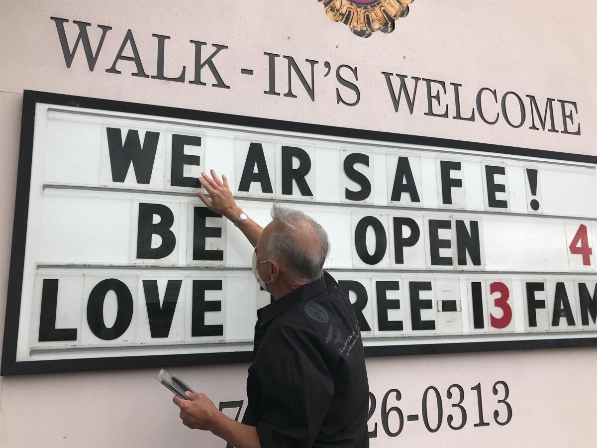 Lester Crowell updates the marquee outside his Marietta, Ga., salon for its reopening. 