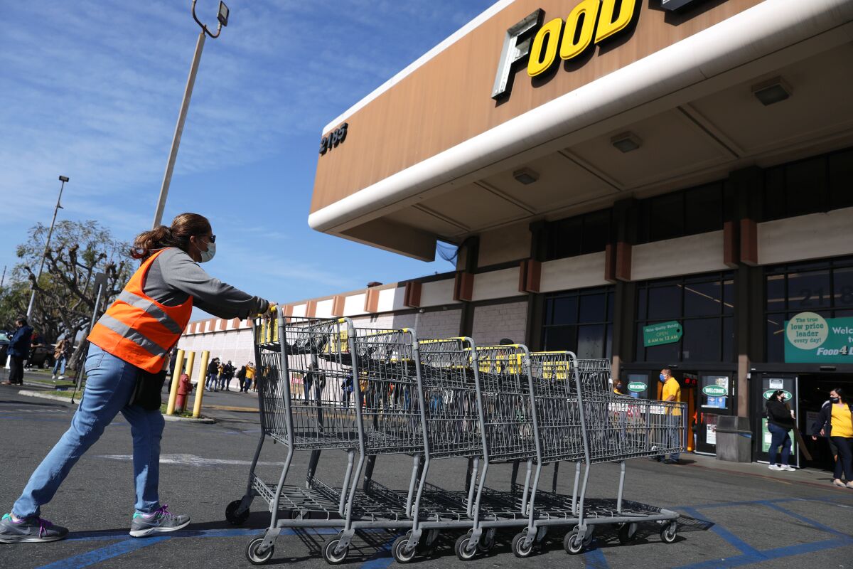 A grocery worker collects carts outside a supermarket.