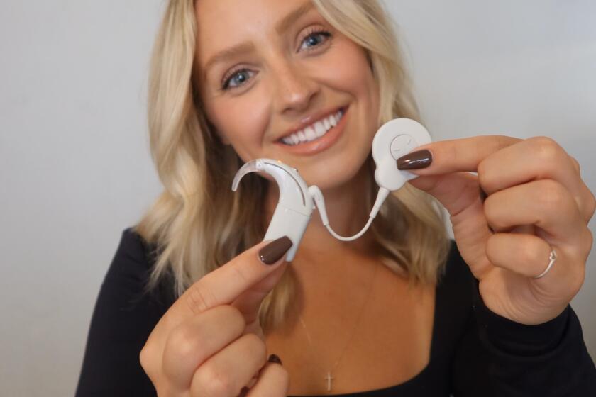 This device helps Daisy Kent hear. Curved portion slips over her ear and magnet senses the cochlear implant under her scalp.