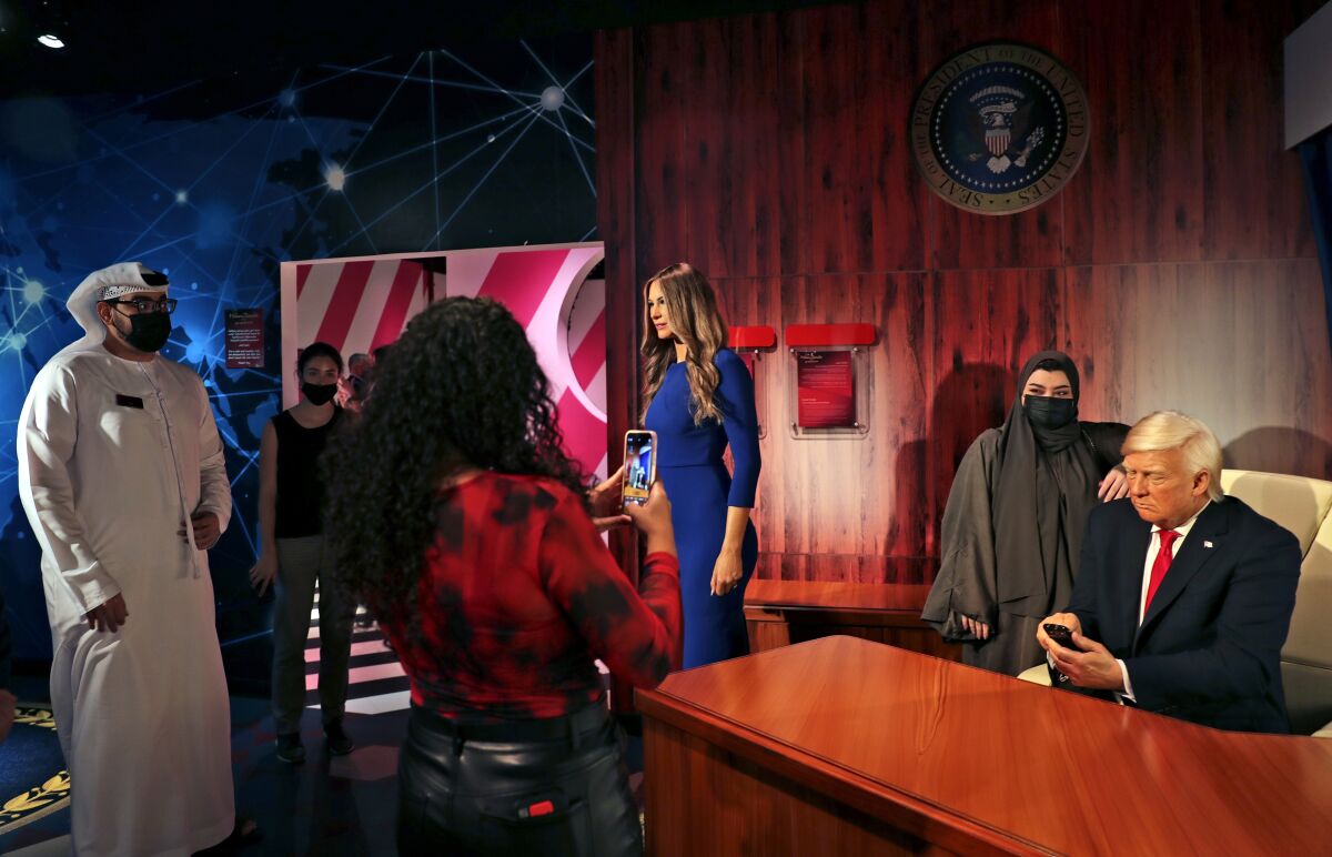 People visit the wax versions of former U.S. President Donald Trump and his wife Melania at the opening of the Madame Tussauds museum, in Dubai, United Arab Emirates, Wednesday, Oct. 13, 2021. The lavish waxworks temple located on a small artificial island off Dubai unveiled 60 celebrities and leaders, from a sultry Kylie Jenner to a beaming Chinese President Xi Jinping, along with a handful of Bollywood dance stars striking poses. (AP Photo/Kamran Jebreili)