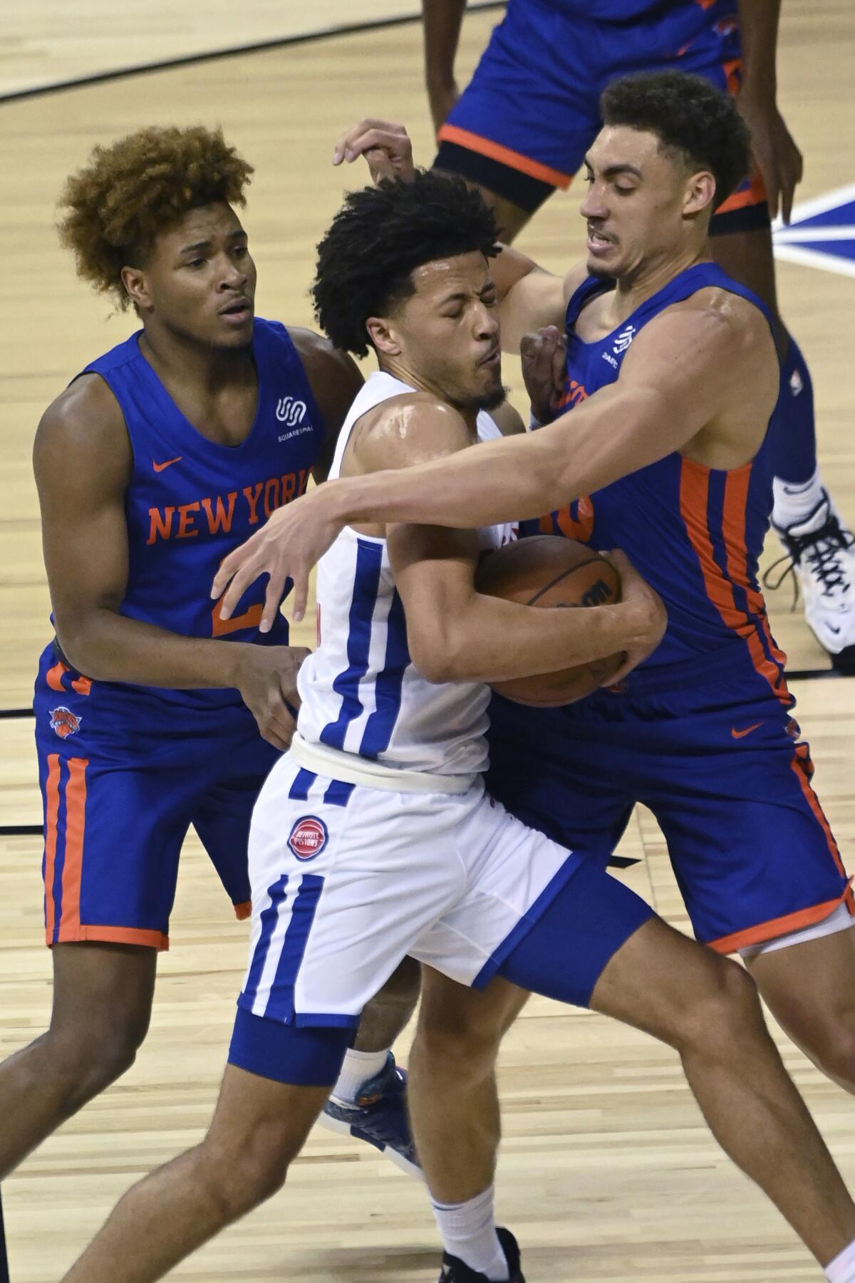 Detroit Pistons guard Cade Cunningham (2) is defended by New York Knicks guard Miles McBride (2) and forward Reid Travis (40) during the first half of an NBA summer league basketball game Friday, Aug. 13, 2021, in Las Vegas. (AP Photo/David Becker)