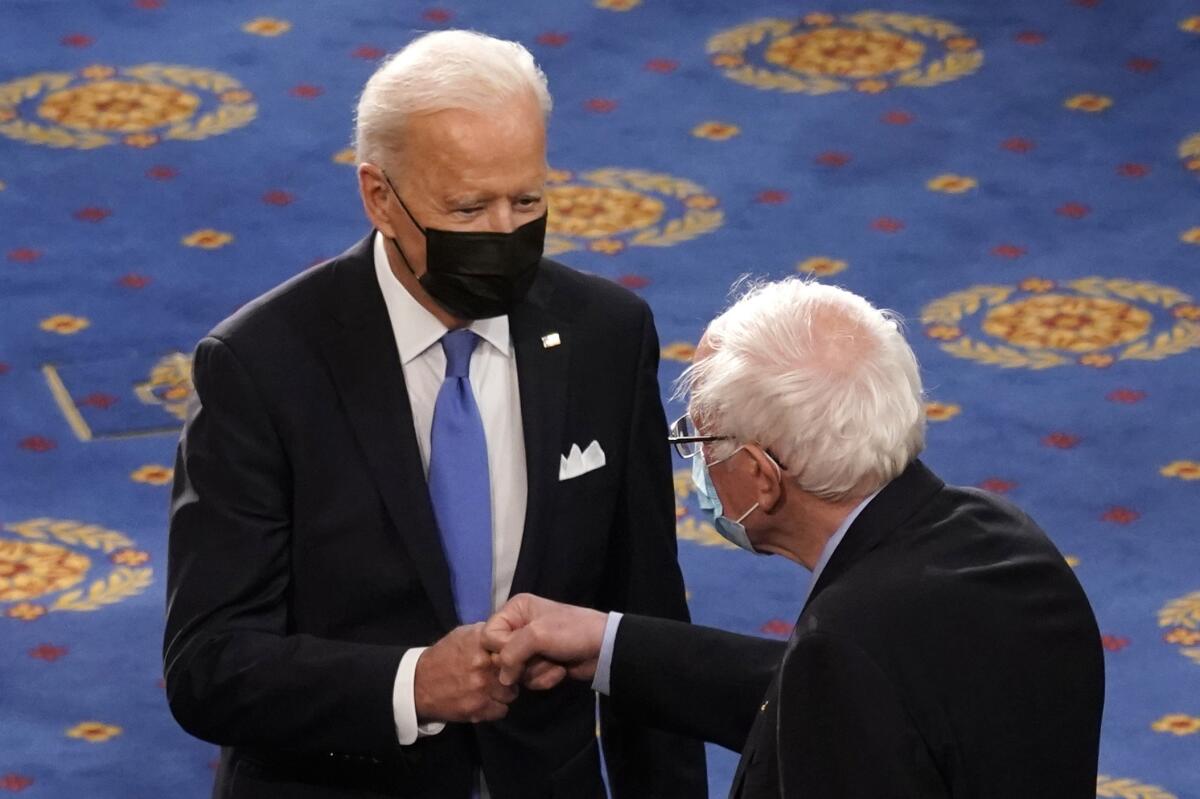 Joe Biden (izq) y Bernie Sanders se saludan al llegar a una sesión conjunta del Congreso en Washington