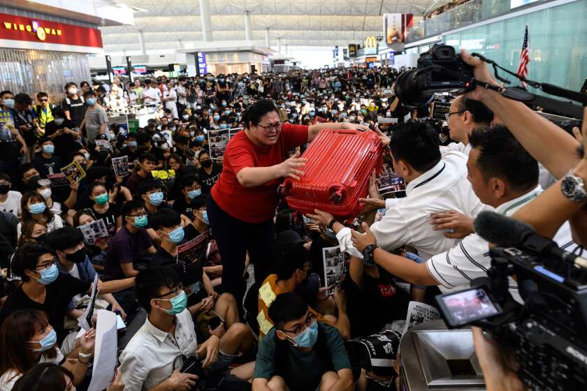 TOPSHOT - A tourist (C) gives her luggage to security guards as she tries to enter the departures gate during another demonstration by pro-democracy protesters at Hong Kong's international airport on August 13, 2019. - Protesters blocked passengers at departure halls of Hong Kong airport on August 13, a day after a sit-in forced authorities to cancel all flights to and from the major international hub. (Photo by Philip FONG / AFP)PHILIP FONG/AFP/Getty Images ** OUTS - ELSENT, FPG, CM - OUTS * NM, PH, VA if sourced by CT, LA or MoD **