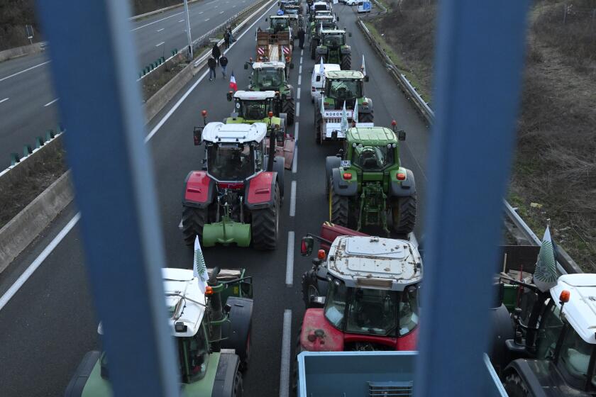Tractors park on a highway, Monday, Jan. 29, 2024 near Roissy-en-France, north of Paris. Protesting farmers vowed to encircle Paris with tractor barricades and drive-slows on Monday, aiming to lay siege to France's seat of power in a battle with the government over the future of their industry, which has been shaken by repercussions of the Ukraine war. (AP Photo/Matthieu Mirville)