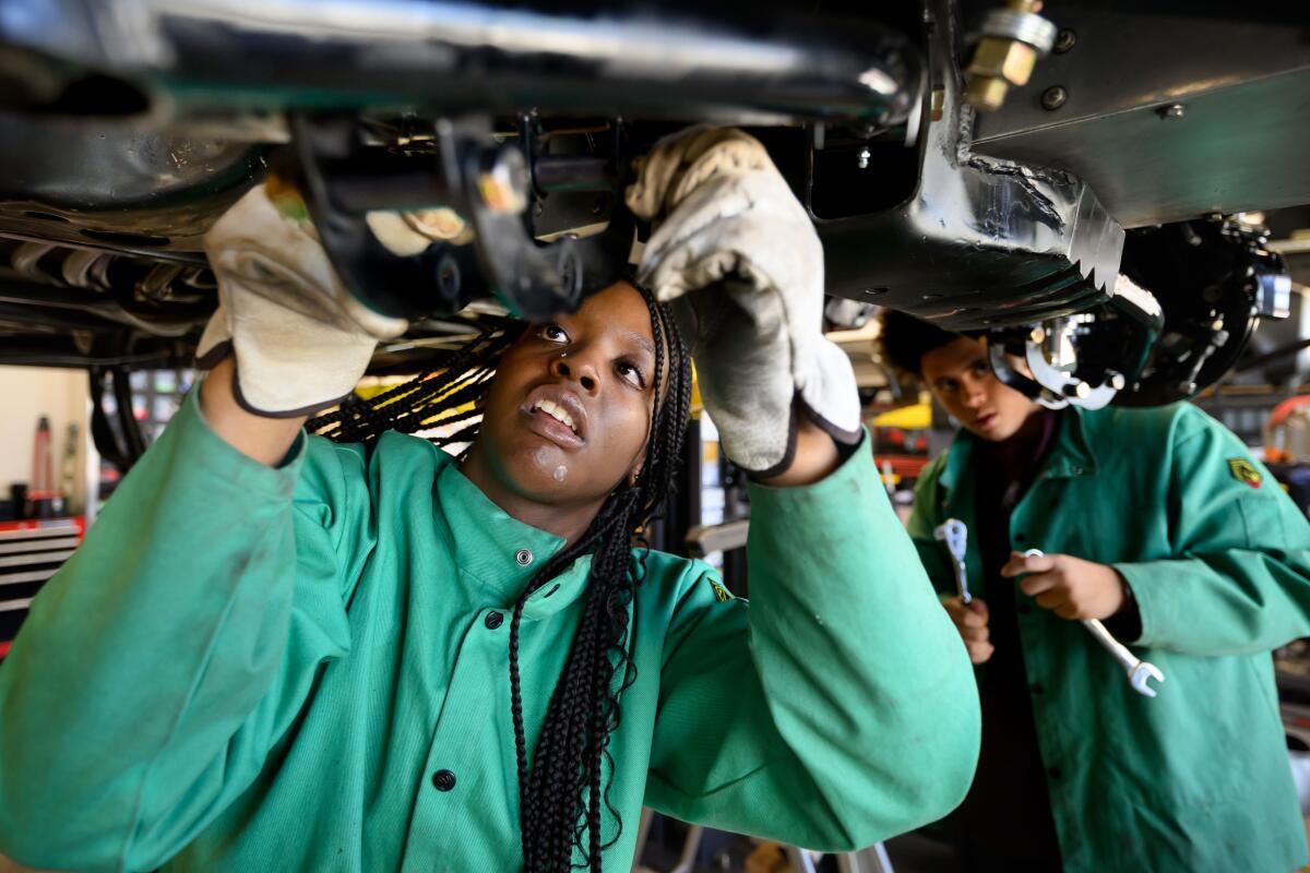 Nushawnti Jones, 18, left, and Marquise Shelton, 17, right, install shocks on a 1969 Chevelle.