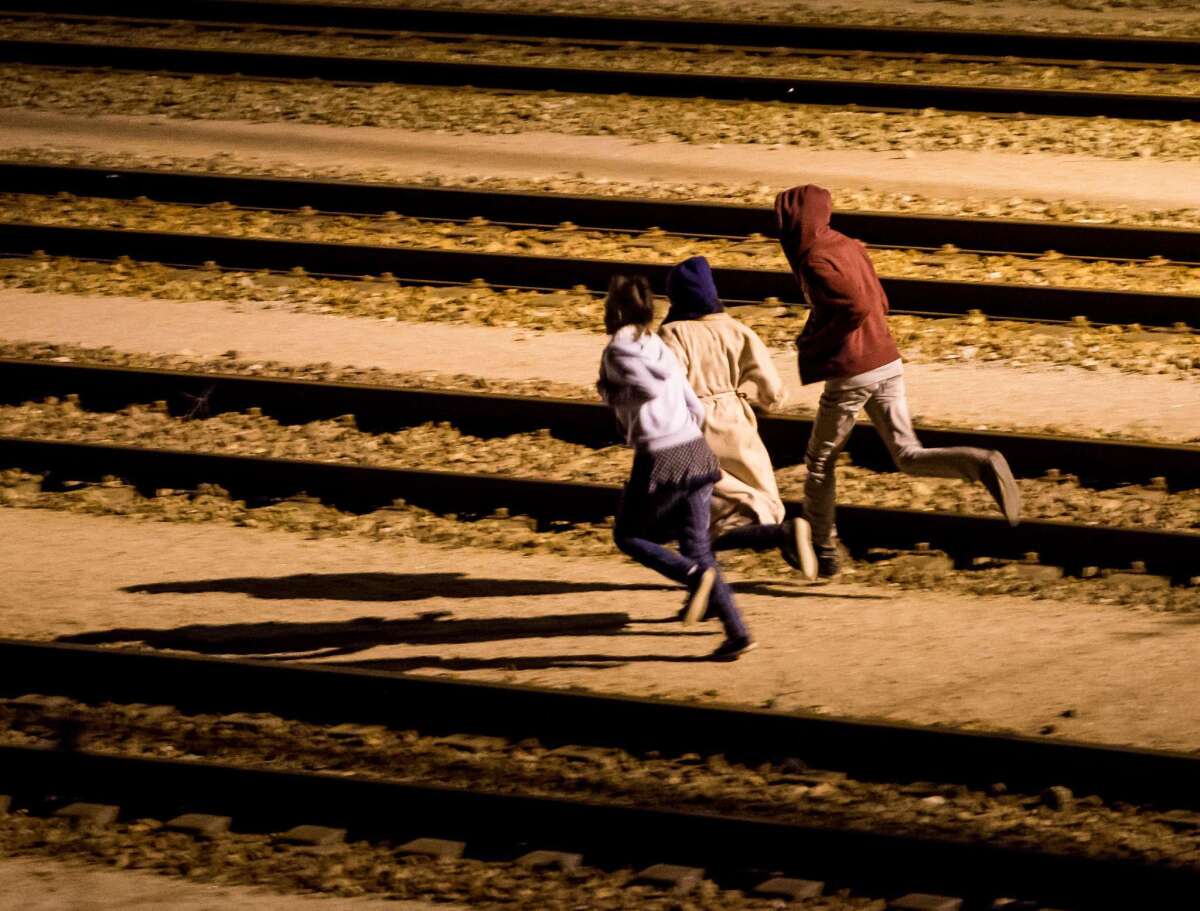 Migrants run on rail tracks in the Channel Tunnel site in Frethun in northern France on Aug. 5. The European Commission has offered to help France and Great Britain deal with the migrant crisis at the Channel Tunnel.