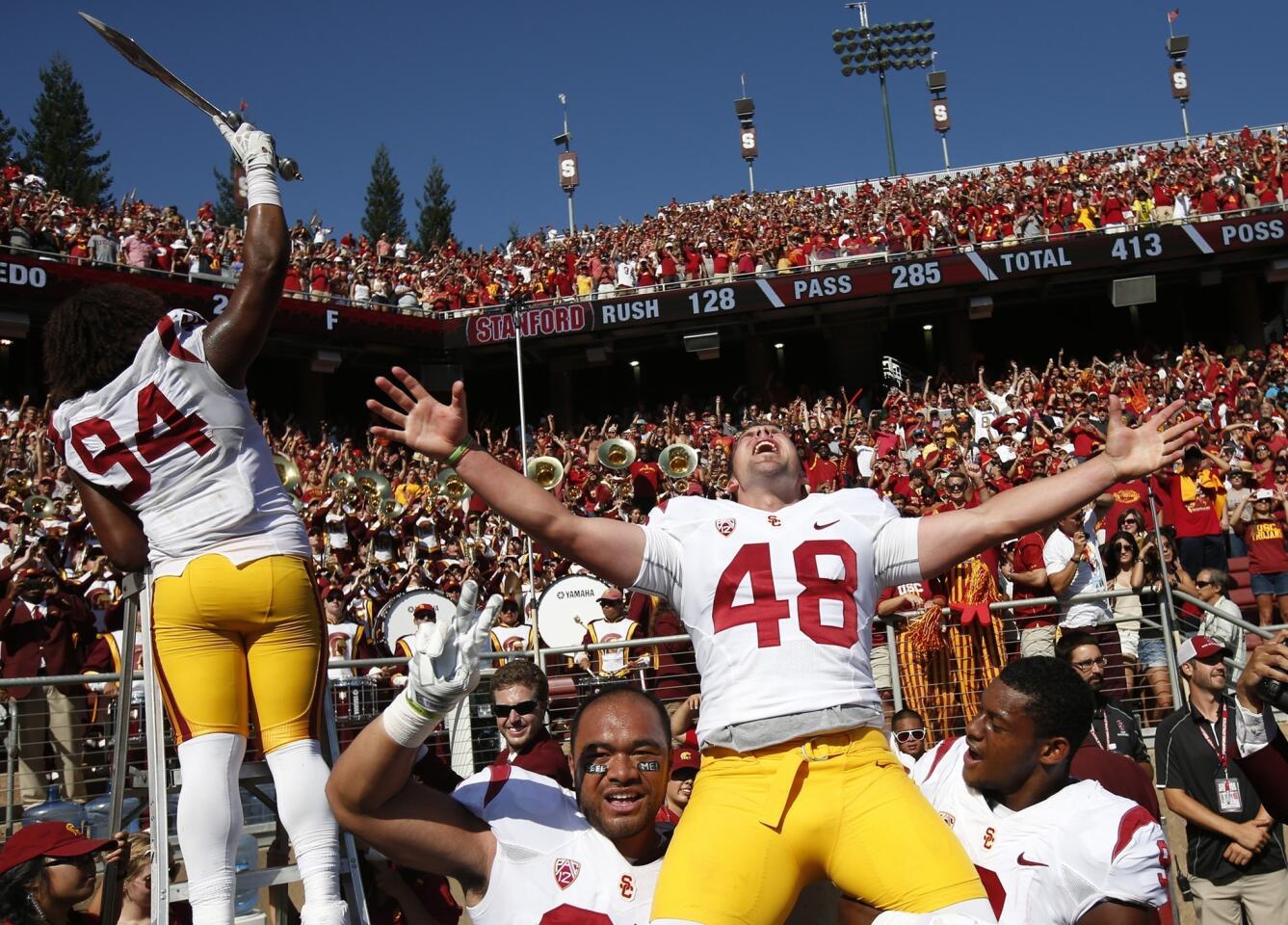 USC kicker Andre Heidari, right, celebrates with teammates Soma Vainuku, left, and Juju Smith as defensive end Leonard Williams leads the band following the Trojans' 13-10 win over Stanford on Saturday.
