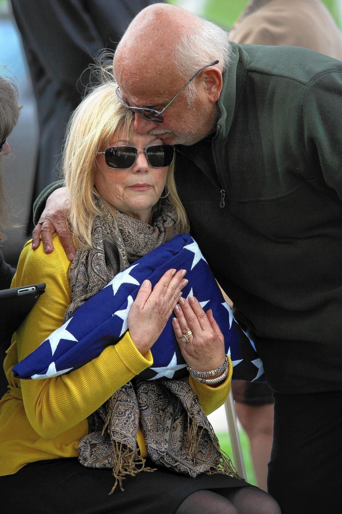 Jill Ellman is hugged by her husband, Richard, as she holds a flag given to her during a memorial service on Wednesday for her father, Air Force Capt. Paul Pascal, whose plane went down at sea in 1957.