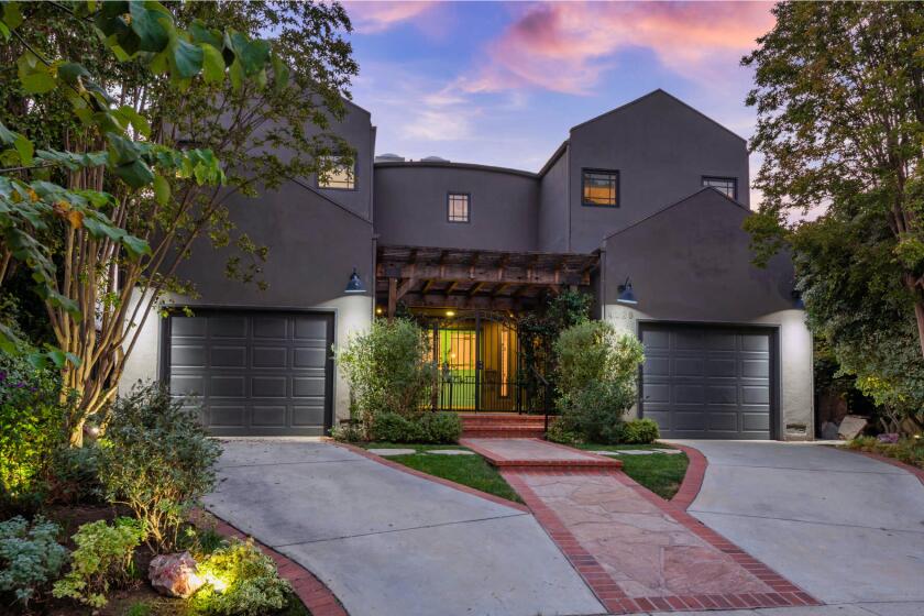 The striking gray home opens to more neutral interiors and a private backyard with a pool under string lights.