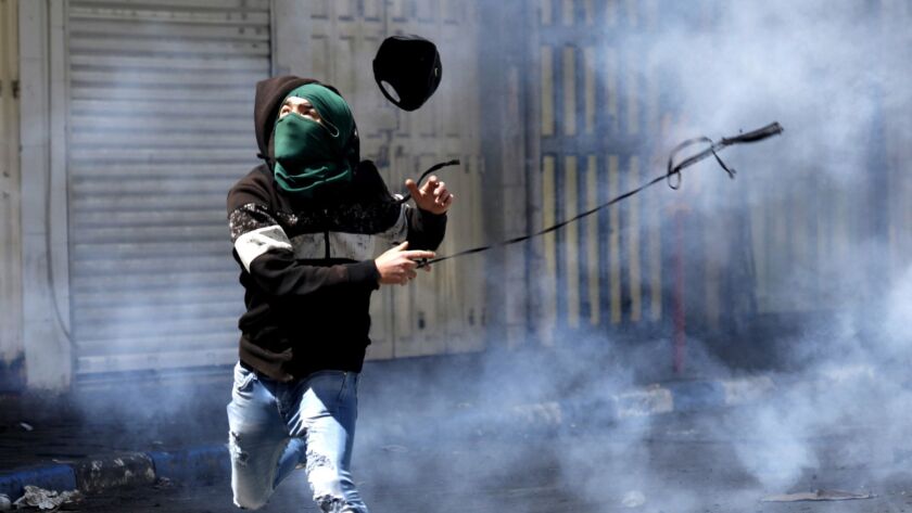 A Palestinian protester throws back a tear gas grenade fired by Israeli troops during clashes in the West Bank city of Hebron on Saturday.