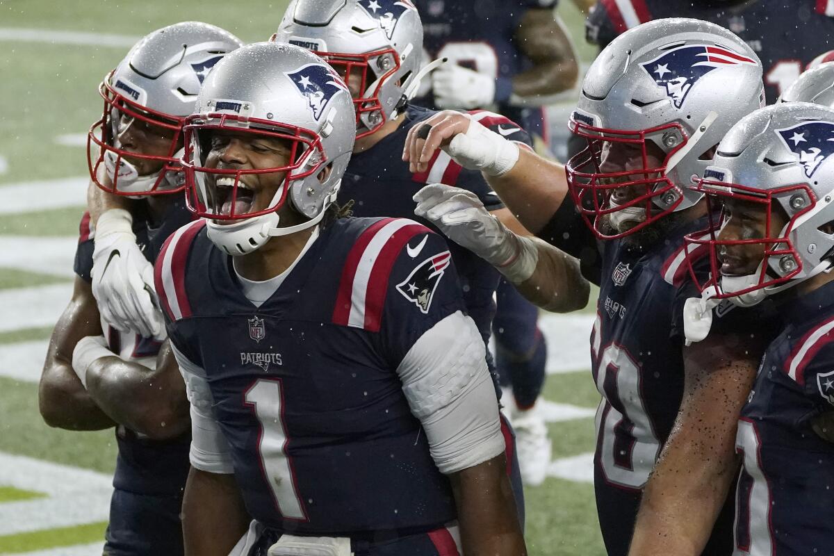 New England Patriots quarterback Cam Newton, left, celebrates after rushing for a touchdown.