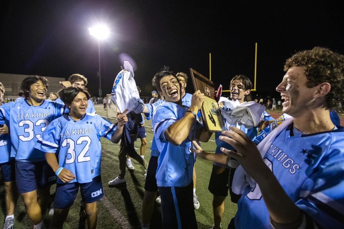 Corona del Mar's Logan Ip, center, celebrates while holding the championship plaque after beating Foothill.