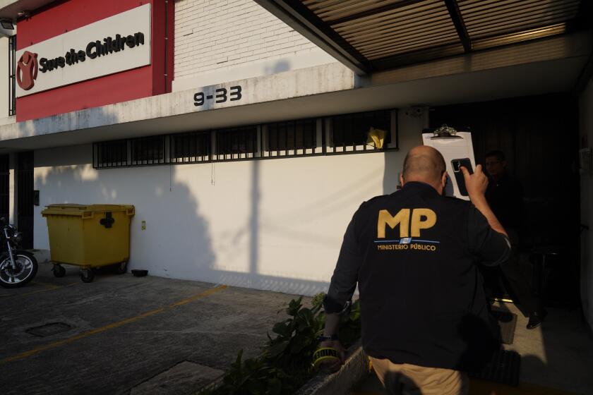 An agent from the Attorney General's office enters Save the Children's headquarters during a raid, in Guatemala City, Thursday, April 25, 2024. The NGO is being investigated for an alleged complaint about the violation of migrant children's rights, according to statements made by prosecutor Rafel Curruchiche. (AP Photo/Moises Castillo)