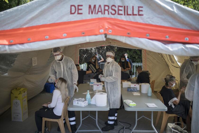 FILE - In this Sept. 24, 2020, file photo, people receive COVID-19 tests at a mobile testing center in Marseille, France. The worldwide death toll from the coronavirus eclipsed 1 million, nine months into a crisis that has devastated the global economy, tested world leaders' resolve, pitted science against politics and forced multitudes to change the way they live, learn and work. (AP Photo/Daniel Cole, File)
