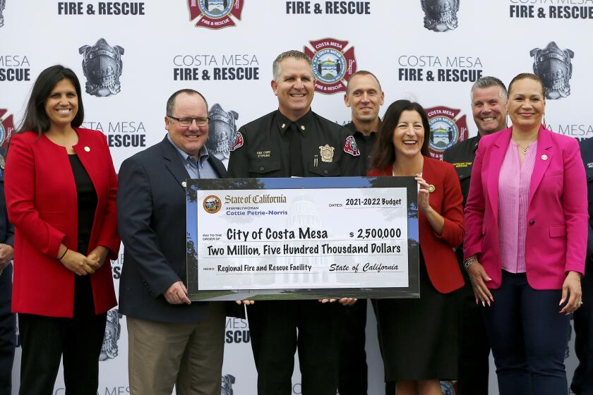COSTA MESA, CA - June 3: Fire Chief Dan Stefano, center, Assemblywoman Cottie Petrie Norris (D-Irvine), second from right, Mayor John Stephens, second from left, City Manager Lori Ann Farrell Harrison, far right, and councilwoman Arlis Reynolds, far left, pose with a $2.5 million check at Costa Mesa Fire Station No. 4 on Friday, June 3, 2022 in Costa Mesa, CA. (Kevin Chang / Daily Pilot)