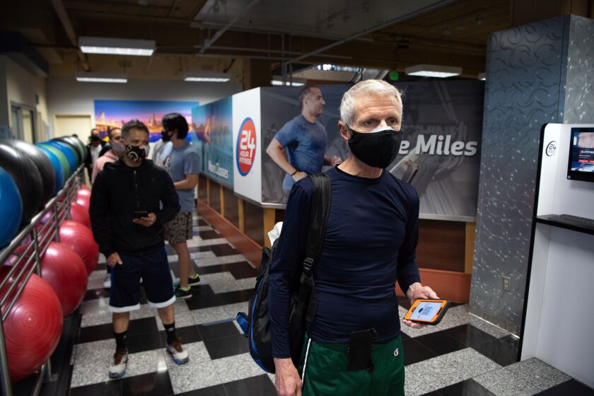 SAN FRANCISCO, CA - MARCH 03, 2021 - Reese Bacon (R) waits in line to check in for his reservation to work out at a 24 Hour Fitness gym in San Francisco, California on March 03, 2021. As San Francisco moves into the red tier of the Covid-19 pandemic, gyms are now allowed to open at a maximum 10% capacity. (Josh Edelson/for the Times)