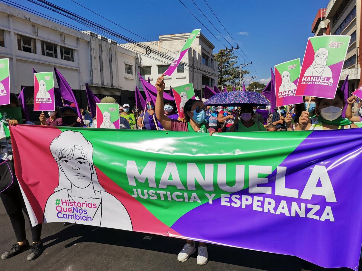 Marchers carry a banner with an image of Manuela.