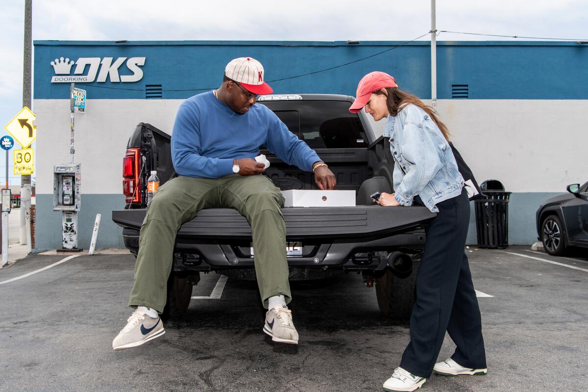 a man and a woman look at a box in the bed of a truck