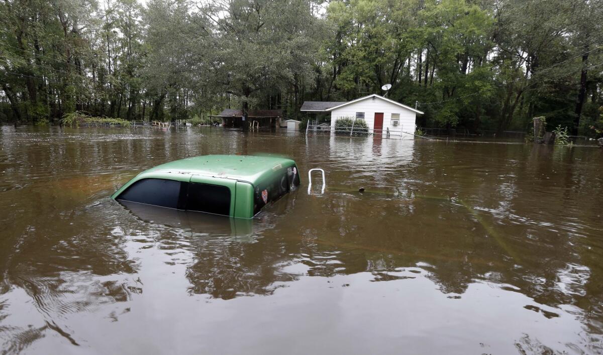 A vehicle and a home are swamped by floodwater from nearby Black Creek in Florence, S.C., on Oct. 5.