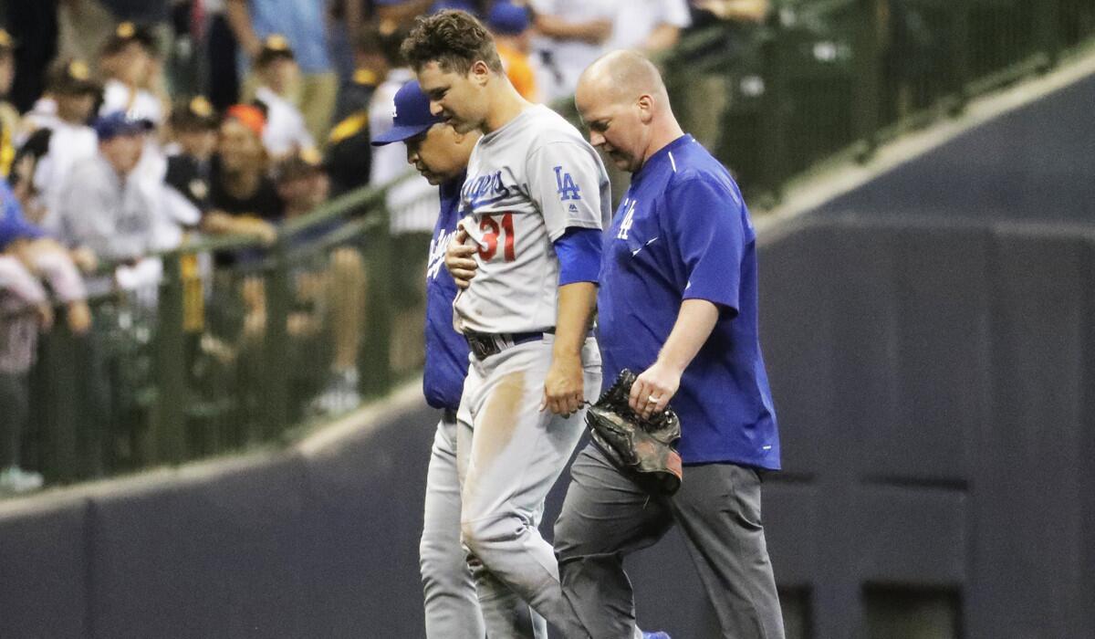 Dodgers' Joc Pederson is helped off the field after an injury during the eighth inning against the Milwaukee Brewers on Tuesday.