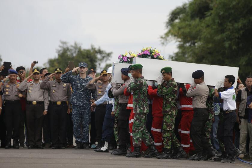 Indonesian soldiers and members of the country's search and rescue agency carry coffins containing victims of the crash of Indonesia AirAsia Flight 8501 at the airport in Pangkalan Bun on Jan. 2.