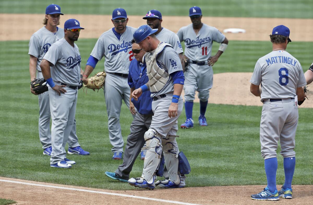 Dodgers catcher Yasmani Grandal (9) is escorted off the field after an injury during the sixth inning against the Nationals.