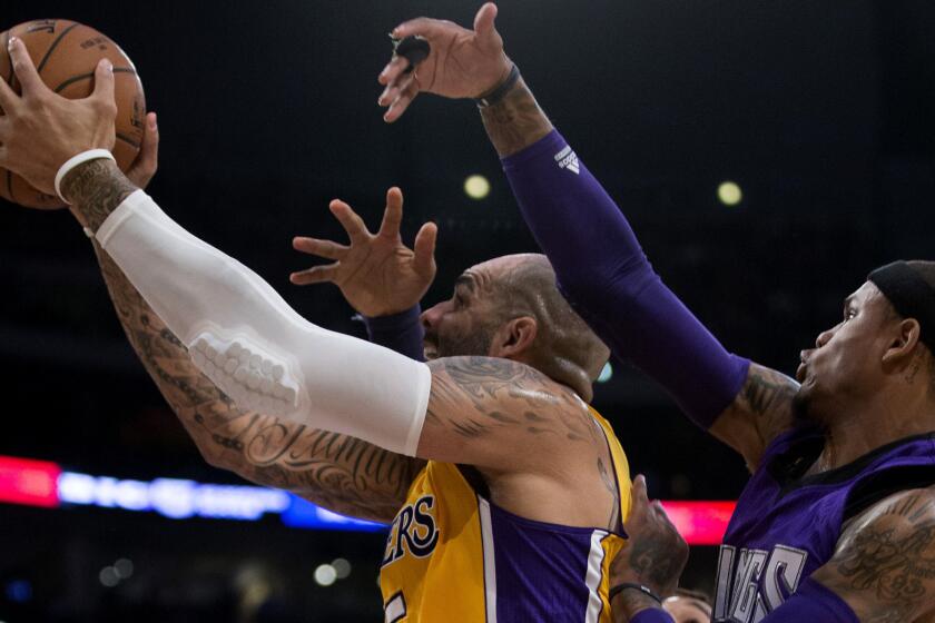 Lakers forward Carlos Boozer drives to the basket against Kings guard Ben McLemore, right, and forward Derrick Williams, rear, in the first half Wednesday night at Staples Center.