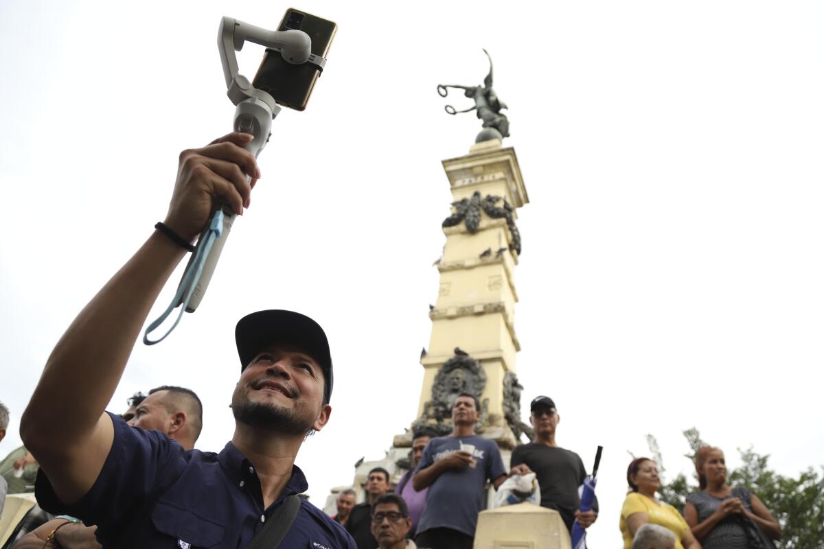 Douglas Guzmán graba un video con su teléfono en la Plaza Libertad, el 24 de junio de 2023, en San Salvador, El Salvador. 