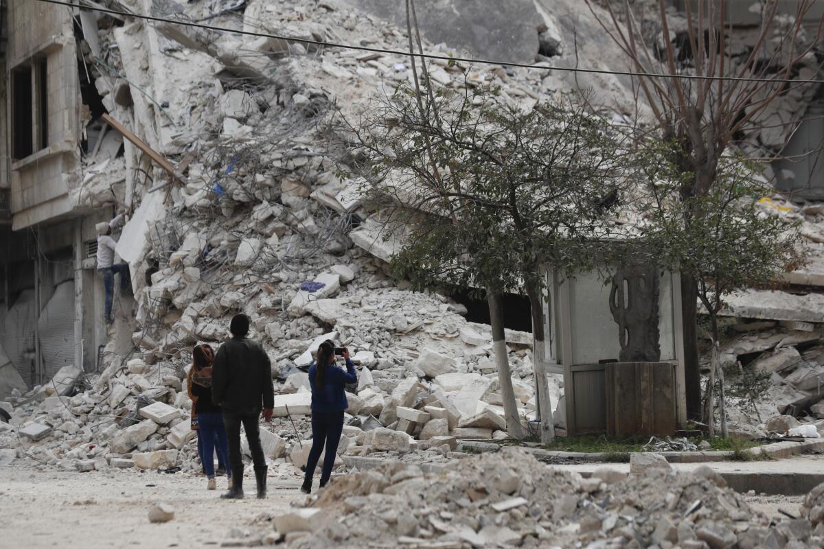 Personas observan un edificio destruido por un terremoto reciente, el lunes 27 de febrero de 2023, en Alepo, Siria. 