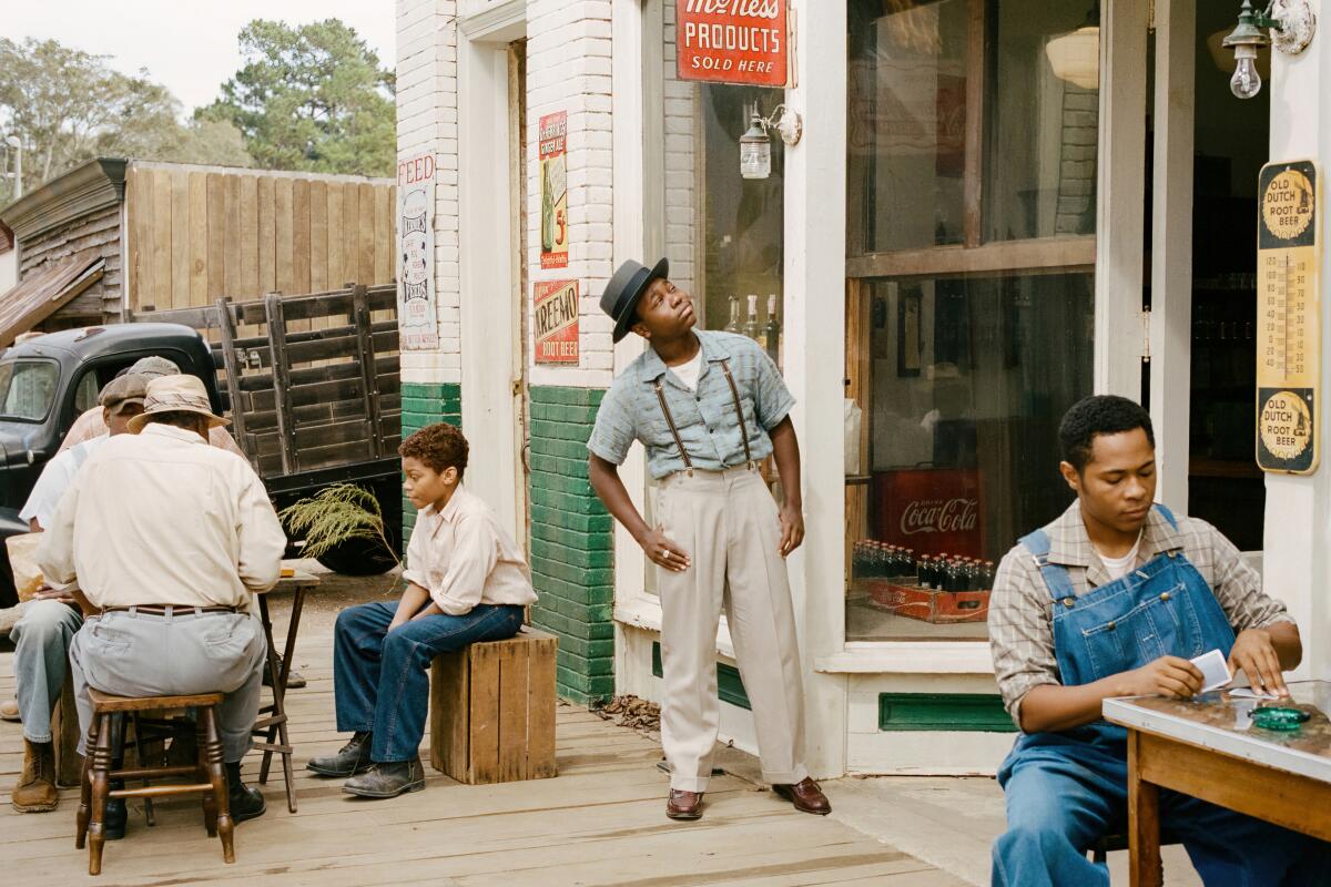 A young man in suspenders and a hat looks up at a store sign.