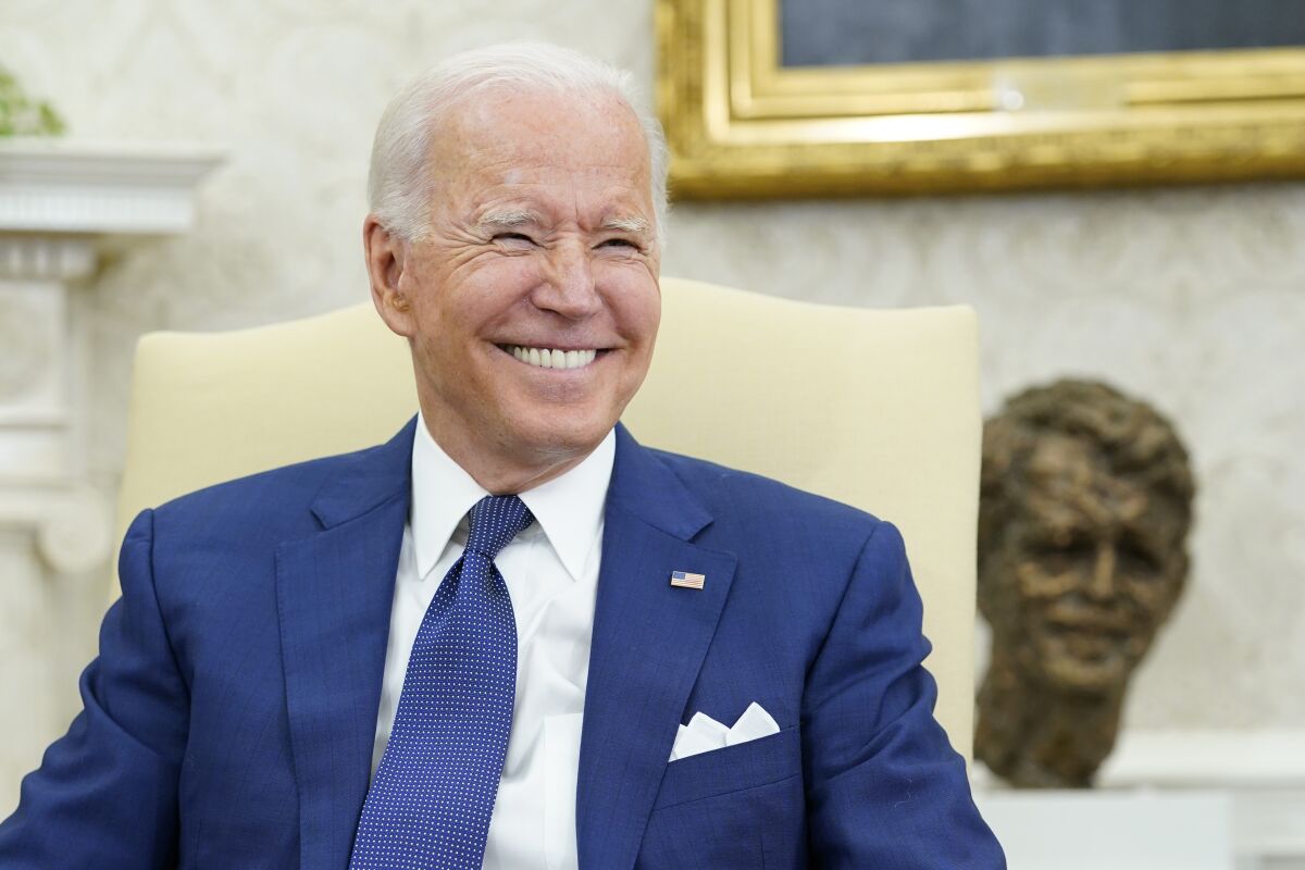 President Biden smiles during a meeting in the Oval Office.