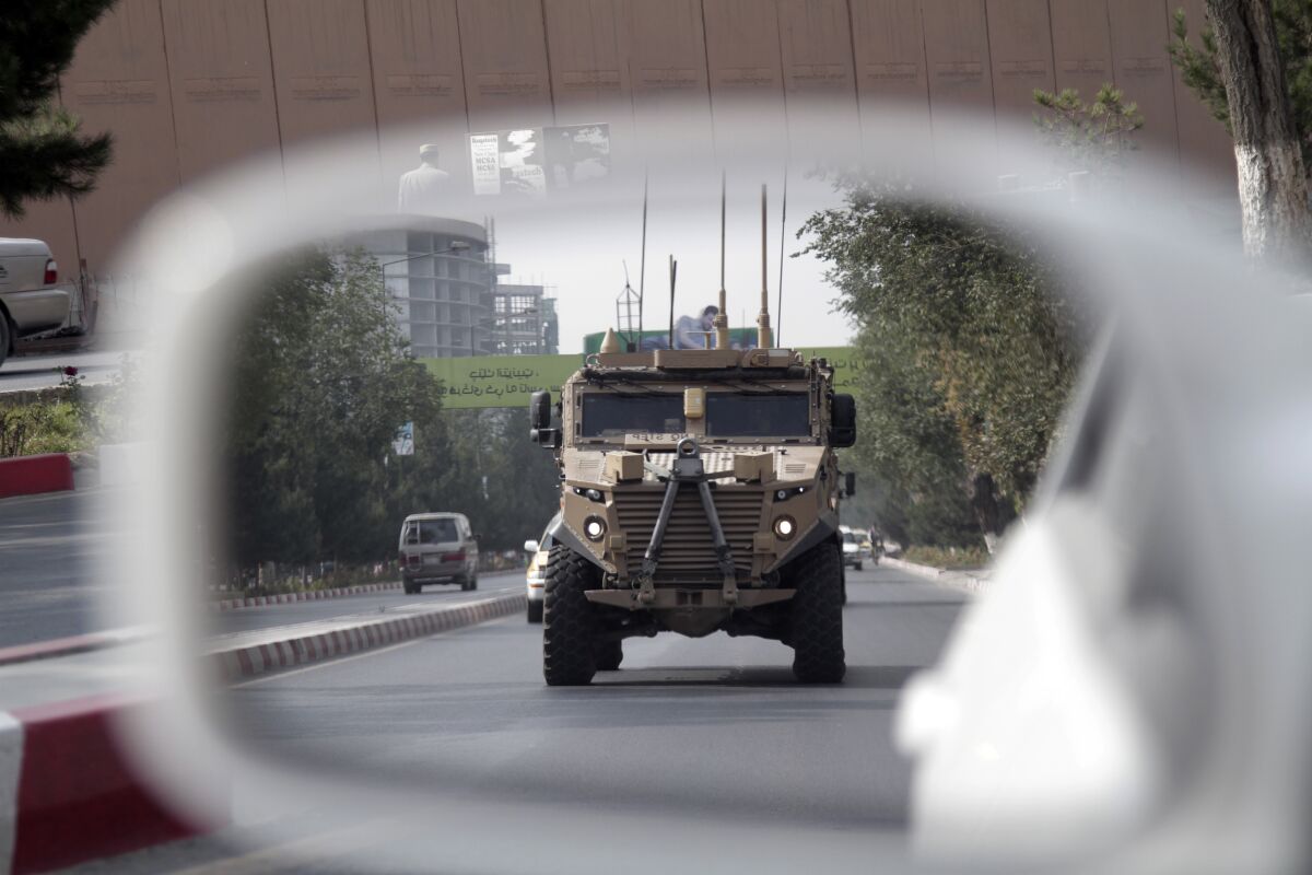 A U.S. armored vehicle is reflected in the mirror of a car in Afghanistan. 