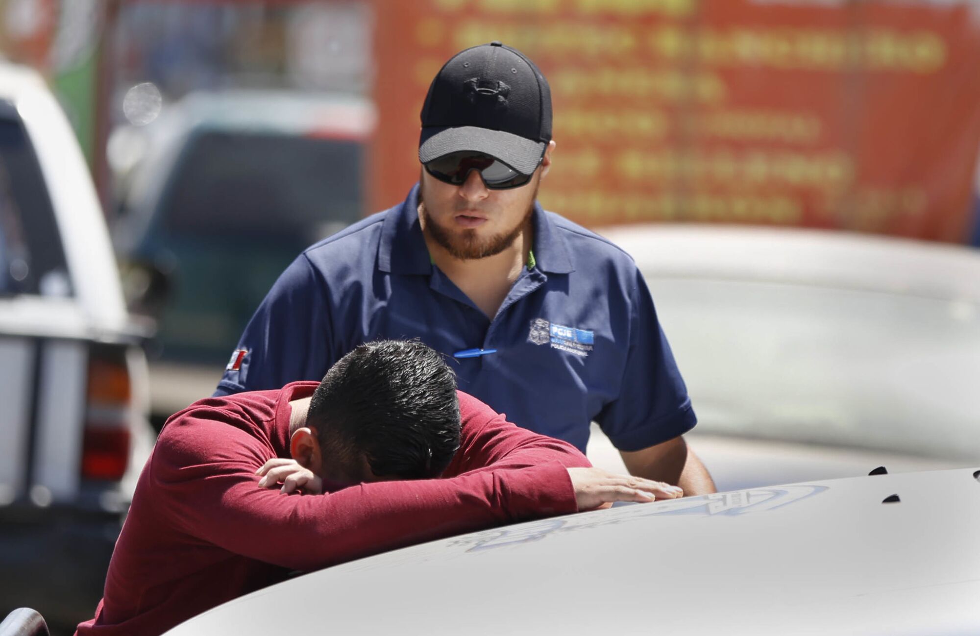 The son of a street vendor in the Buena Vista section of Tijuana cries on the hood of a police car 