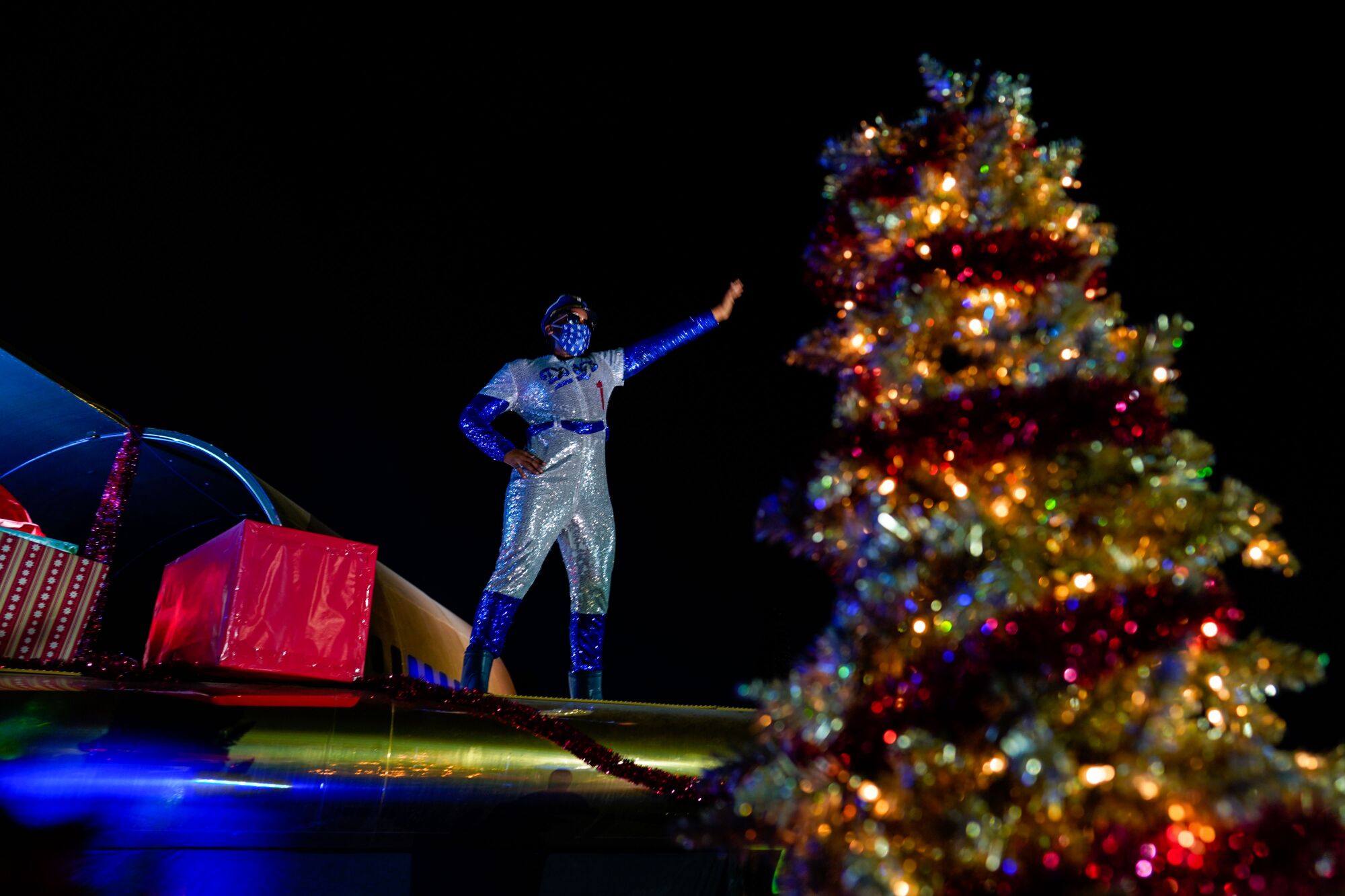 A performer decked out in a Christmas themed dodger costume dances and waves at cars