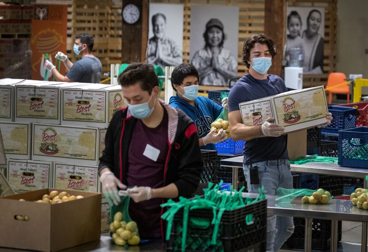 Jose Secundino and other temporary employees in face masks pack boxes at an Orange County food bank.