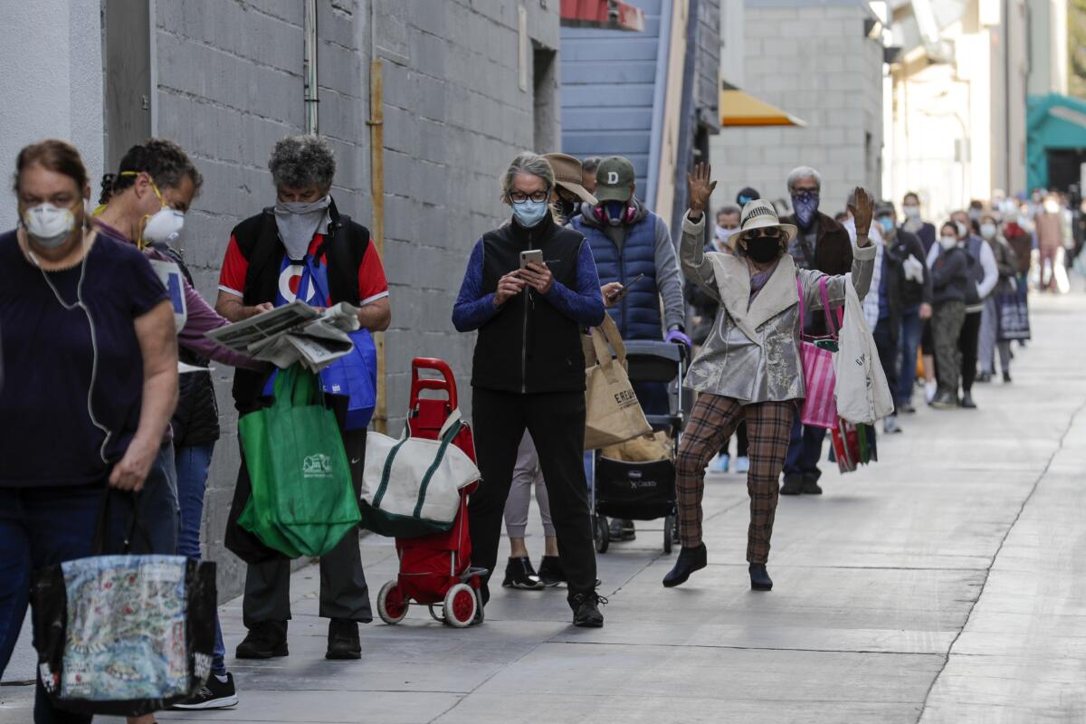 Customers wait in long line because of controlled entry into the Santa Monica farmers market dictated by coronavirus pandemic restrictions. 